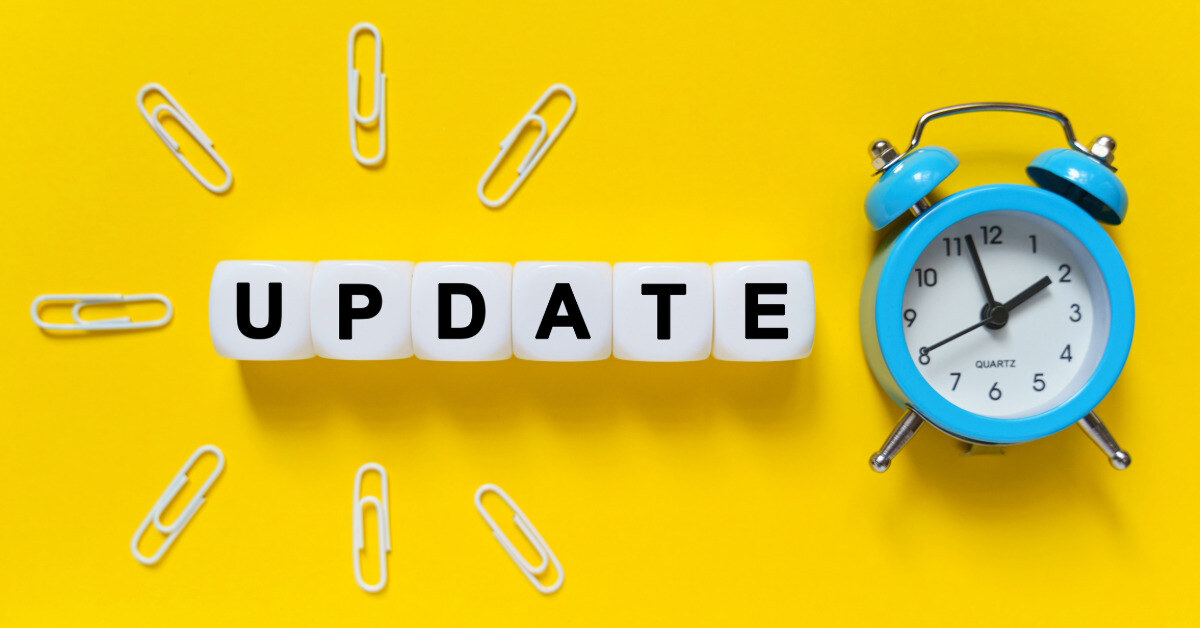 On a yellow background, a blue alarm clock, paper clips and white cubes on which the text is written - UPDATE
