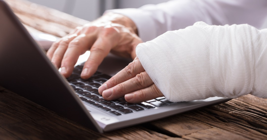 Close-up Of A Businessperson`s Hand With Hand Injury Using Laptop
