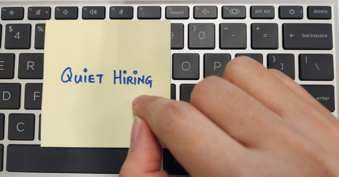 A person pointing at a note with words Quiet Hiring written on it