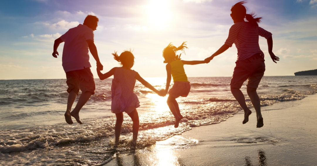 Happy family jumping together on the beach