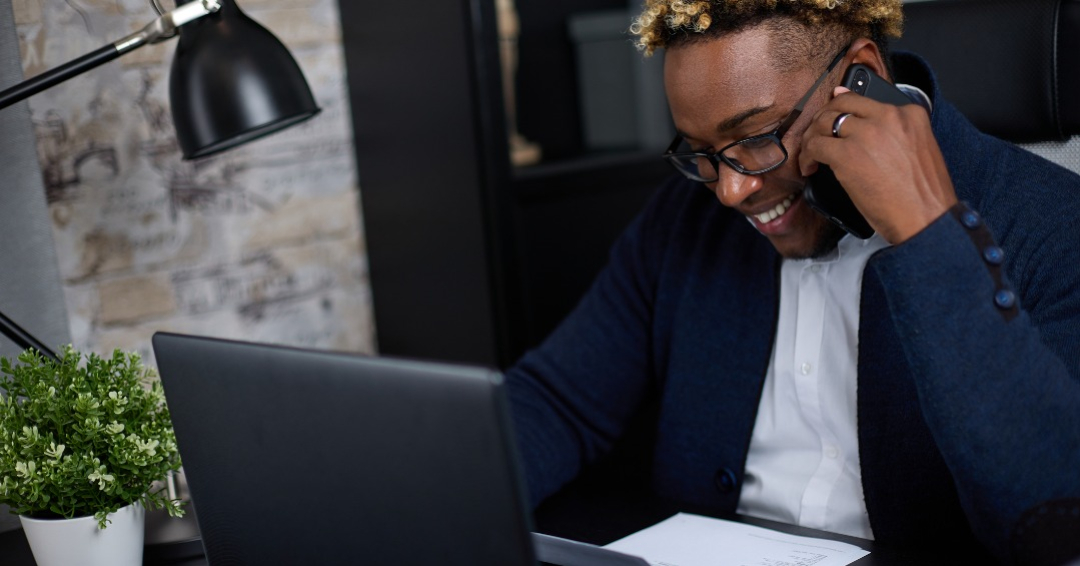 Smiling African-American businessman, HR, employer, holds a resume document in his hands, asks questions to candidate for a position on mobile phone, clarifies the information specified in the resume