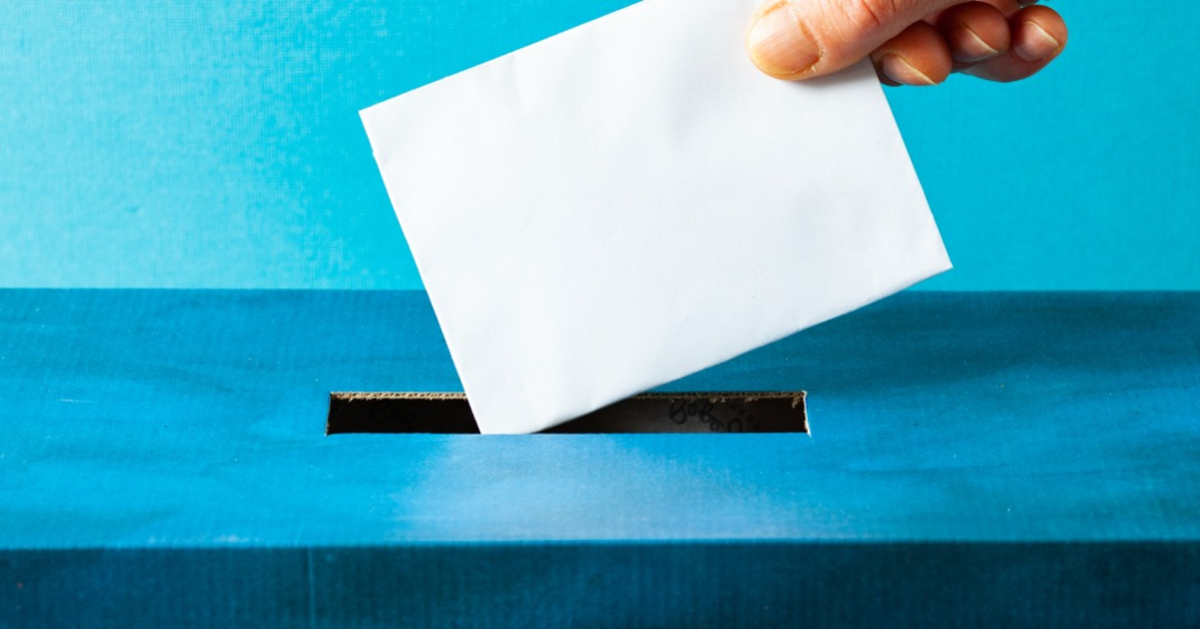 hand putting ballot in blue box