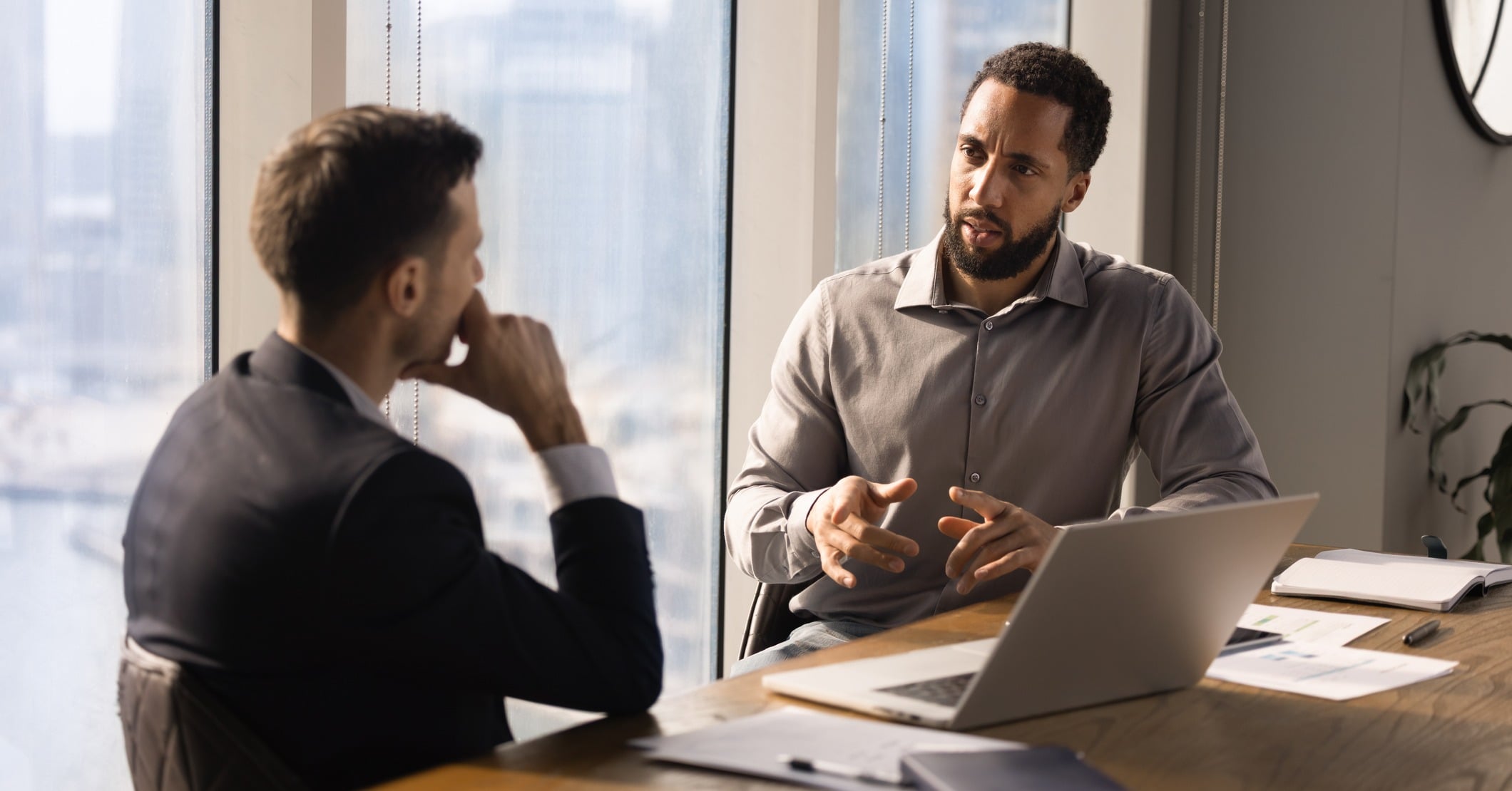 Two men sit in a meeting room in conversation