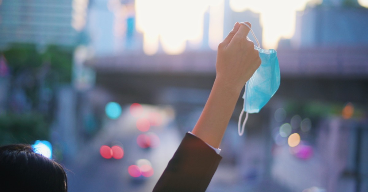 person holding mask in air over cityscape