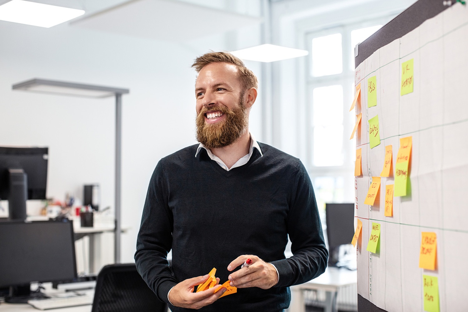GettyImages-1180182861-Confident bearded businessman looking away while standing by bulletin board in creative office-1