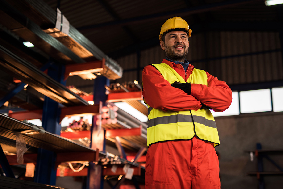 GettyImages-624497670-Below view of happy worker with crossed arms in warehouse