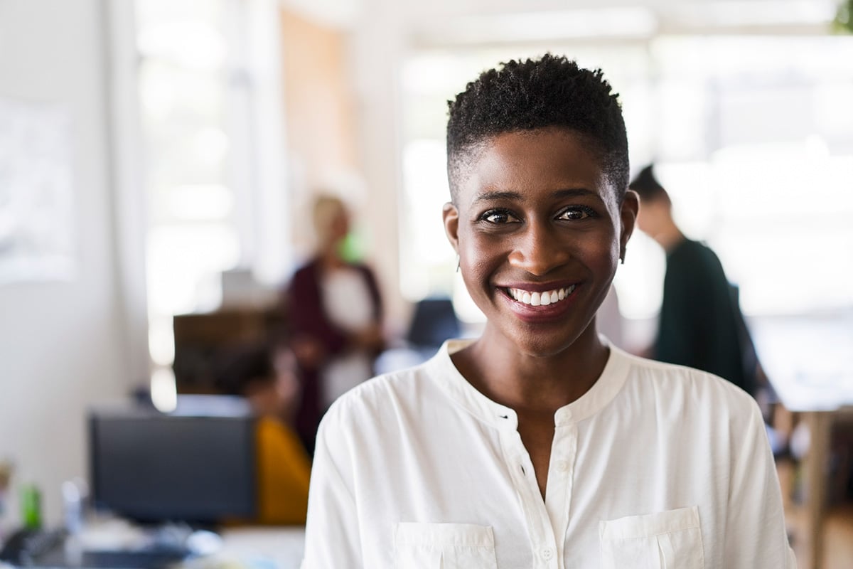 GettyImages-919502288-Close-up portrait of businesswoman smiling in office. Confident female professional is at workplace. She is wearing smart casuals.