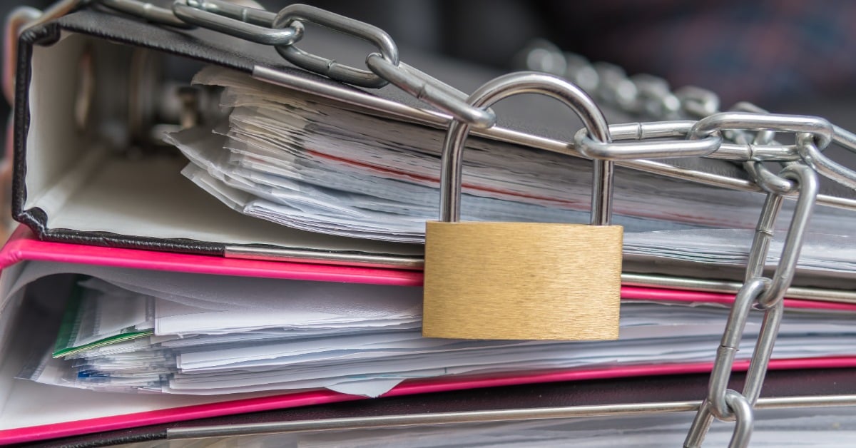 image of folders filled with paper with a lock and chain draped over them