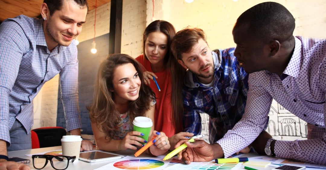 Portrait of happy young people in a meeting looking at camera and smiling. Young designers working together on a creative project.